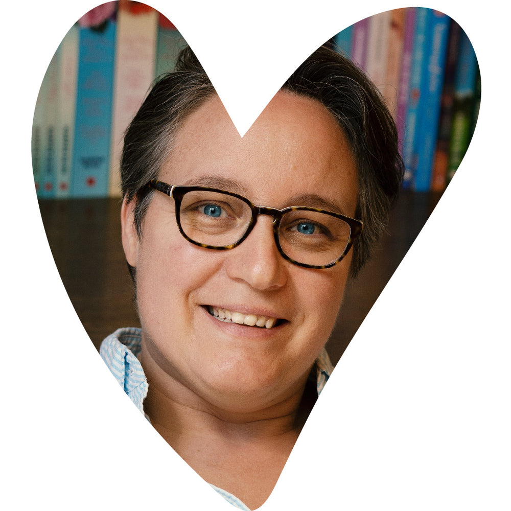 Portrait de l’autrice Harper Bliss, souriante et portant des lunettes, recadré dans une forme de cœur, avec une bibliothèque floue en arrière-plan.